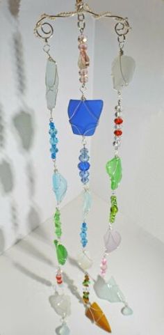 a wind chime with many different colored beads hanging from it's side on a white surface