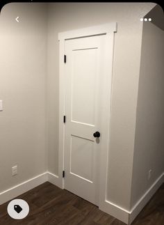 an empty room with a white door and wood floor