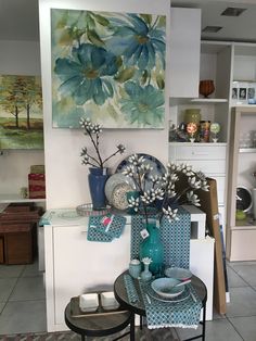 a table with plates and vases sitting on top of it next to a painting