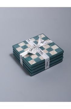 four green and white checkerboard coasters with ribbon tied around the edges, stacked on top of each other