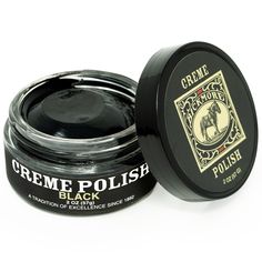 a jar of black creme polish sitting on top of a white table next to it's lid