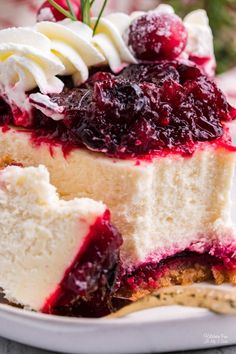 a piece of cheesecake on a plate with whipped cream and cranberry sauce