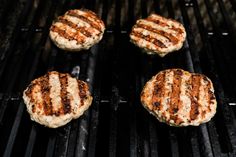 four hamburger patties cooking on a grill