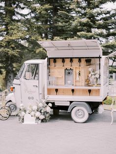 an ice cream truck is decorated with white flowers and greenery for a wedding ceremony