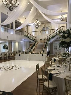 an elegant wedding reception set up with chandeliers and white drapes on the ceiling