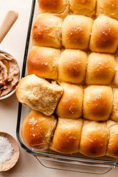 several rolls in a glass baking dish next to a bowl of peanut butter