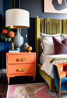 a bedroom with blue walls, orange and yellow furniture and paintings on the wall above it