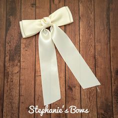 a white bow with the word stephanie's bows on it sitting on top of a wooden floor