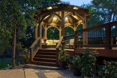 a wooden gazebo sitting on top of a patio next to a lush green forest