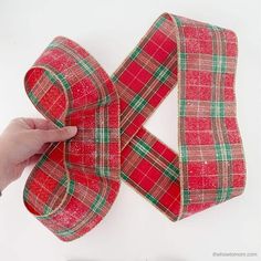 someone is making a bow out of plaid fabric and ribbon with the help of scissors