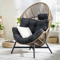 a wicker chair with black cushions and white pillows