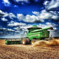 a big green truck driving down a dirt road