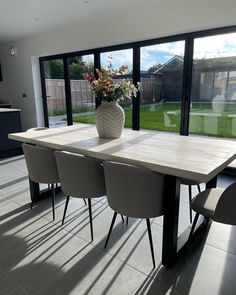 a dining room table with chairs and a vase filled with flowers on top of it