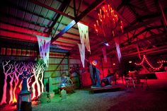 the inside of a building lit up with red and blue lights, trees and streamers