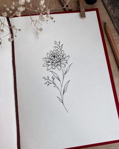 an open notebook with a drawing of a flower on it next to some pencils