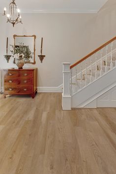 an empty room with wooden floors and white railings on the wall, next to a staircase