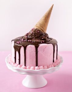 a pink cake with chocolate icing and an ice cream cone on top