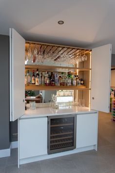 a bar with wine glasses and bottles on the top shelf in a room that looks like it is being used as an office