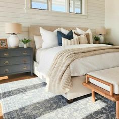 a large bed sitting next to two windows in a bedroom on top of a blue rug