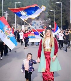 a woman and child are walking down the street with flags in front of them,