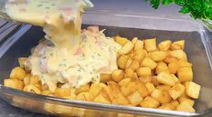 a person pouring dressing over potatoes in a glass dish