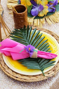 a table setting with pink and yellow plates, flowers and napkins on the plate