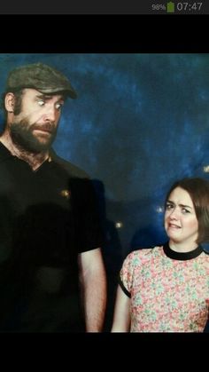 a man and woman standing next to each other in front of a blue wall with lights