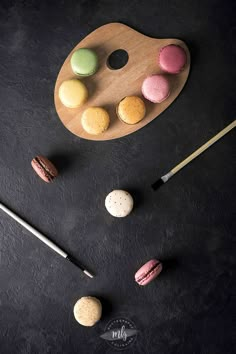 macaroni and cheeses are arranged on a wooden tray next to an artist's palette