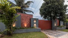 an outdoor area with some trees and lights on the wall, along with a brick walkway