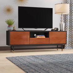 a flat screen tv sitting on top of a wooden entertainment center next to a lamp