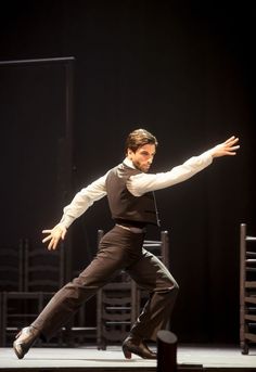 a man in black vest and tie dancing on stage