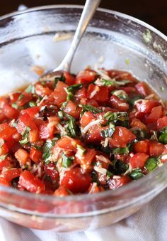 a glass bowl filled with chopped tomatoes and herbs