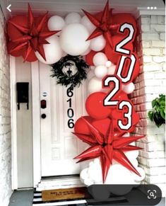 the front door is decorated with red and white balloons, starbursts, and a wreath