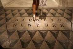 a woman standing in front of a mosaic floor with the words, barnneys's new york written on it