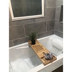 a bathtub with a plant in it and a wooden tray on the tub's side