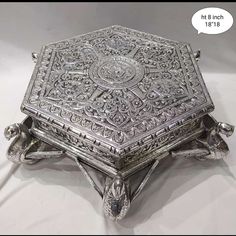 an ornate silver box sitting on top of a white surface with a speech bubble above it