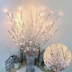 two vases filled with branches and lights on top of a white tablecloth covered floor