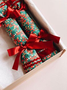 two wrapped presents in a box with red ribbon