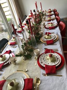 the table is set for christmas dinner with red napkins and gold place settings, silverware