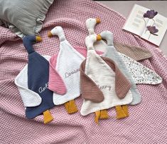 four ducks are laying on a bed with pink sheets and pillows next to an open book