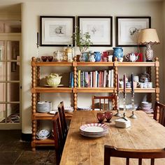 a wooden table topped with plates and bowls next to a book shelf filled with books