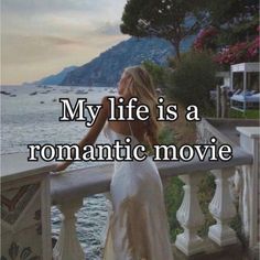 a woman standing on top of a balcony next to the ocean with text that reads, my life is a romantic movie