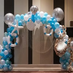 an arch made out of balloons and seashells is displayed in front of a mirror