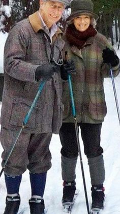 an older man and woman standing on skis in the snow