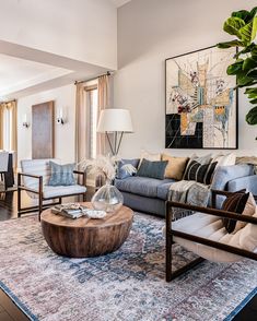 a living room filled with furniture and a large painting on the wall above it's fireplace