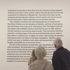 two people standing in front of a white wall with text on it and another person looking at the wall