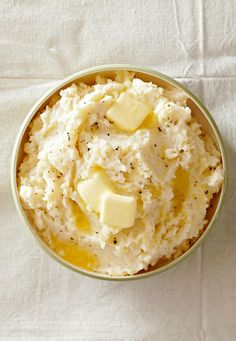 a bowl filled with mashed potatoes on top of a white cloth next to a bottle of wine