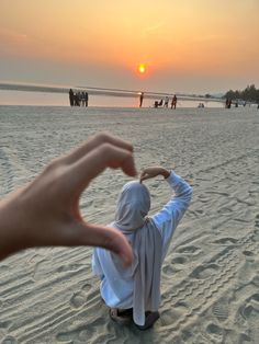 a person sitting in the sand with their hand up