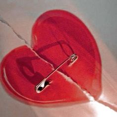 a red heart shaped object with two pins in it