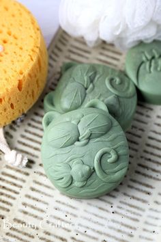 two green soaps sitting on top of a table next to a white flower vase